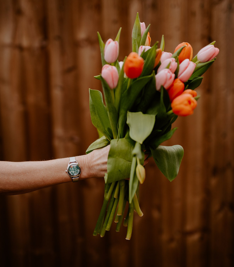 Holding spring flowers while wearing Slow Down watch