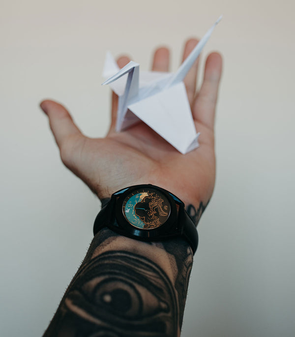 Paper crane watch on wrist holding paper crane